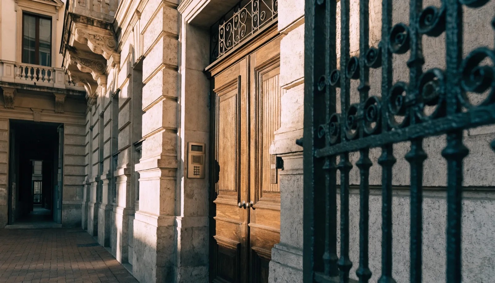 Portone d'ingresso di un elegante palazzo milanese con citofono, luce calda pomeridiana