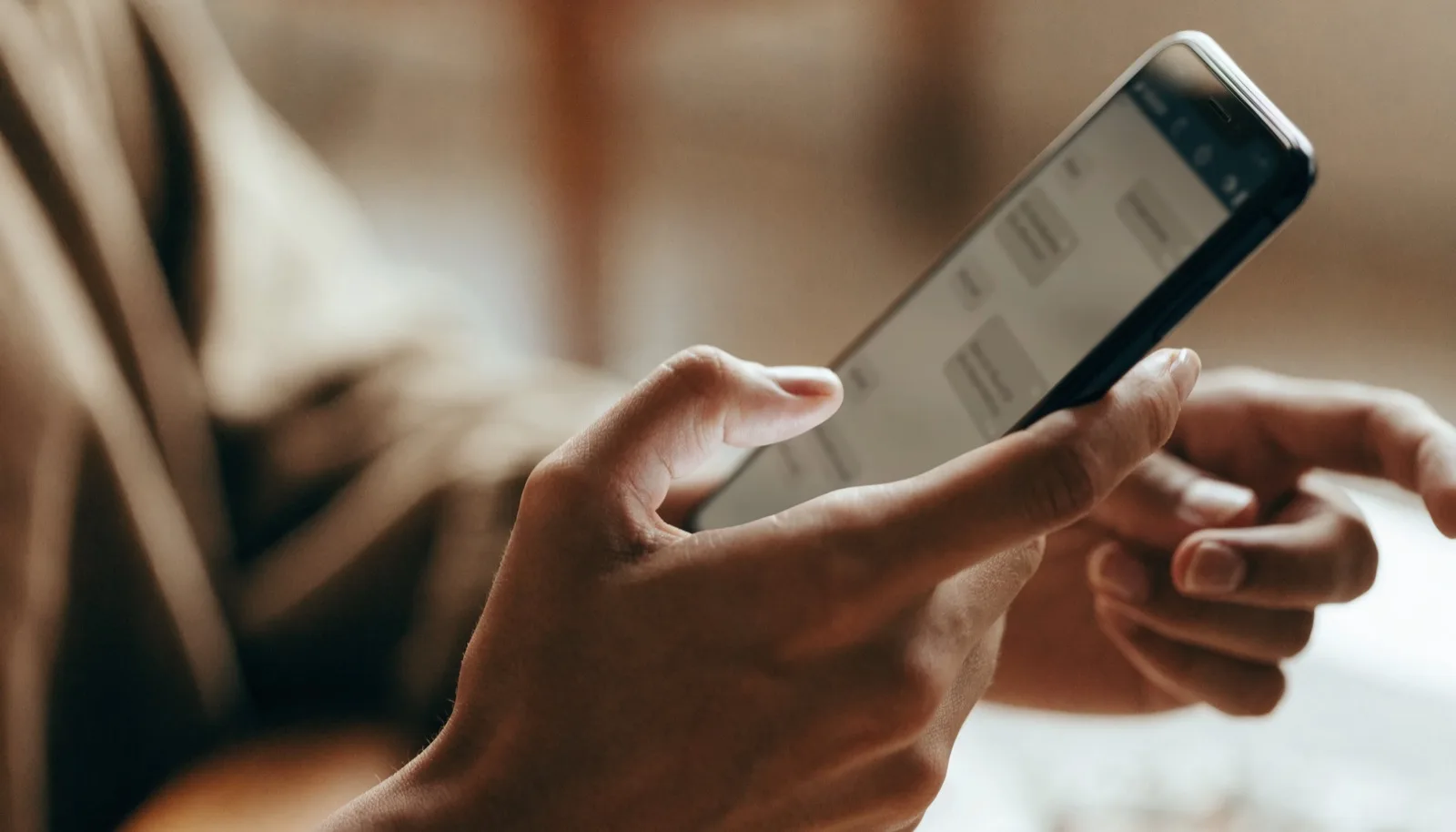 Mani che tengono uno smartphone con una conversazione sfocata