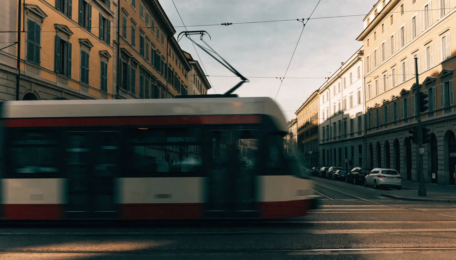 Tram di Milano che passa su una strada cittadina fiancheggiata da edifici, luce pomeridiana
