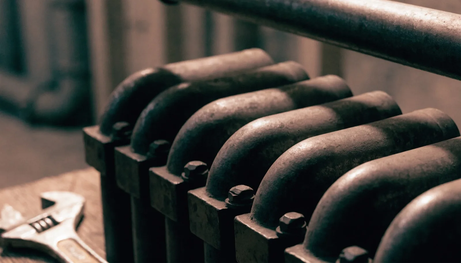 Primo piano di un vecchio termosifone con una chiave inglese appoggiata vicino